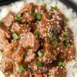 Beef teriyaki over rice topped with sesame seeds and diced green onions.