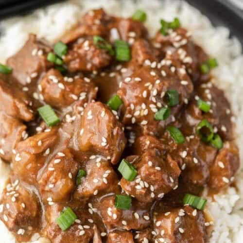 Beef teriyaki over rice topped with sesame seeds and diced green onions.