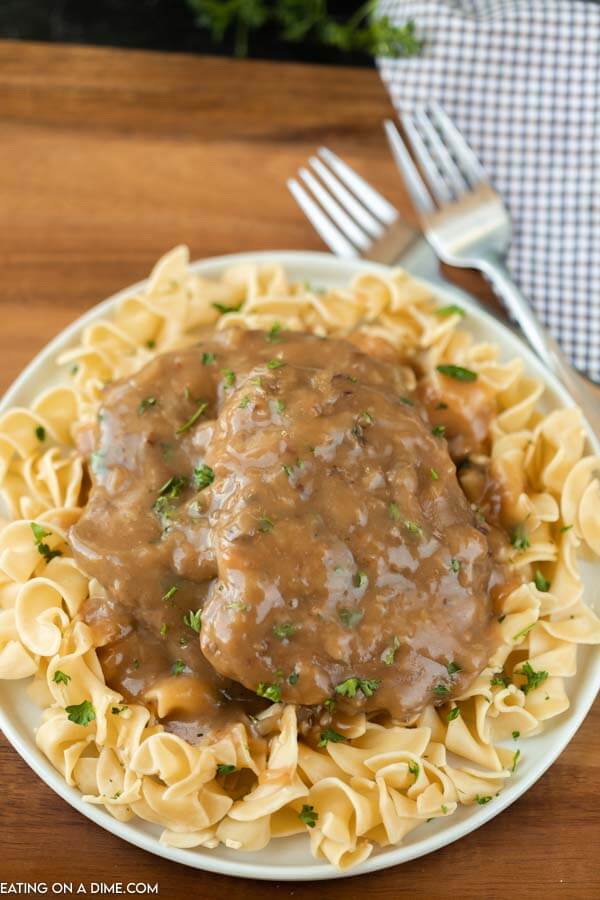 white plate with egg noodles and cube steak and gravy