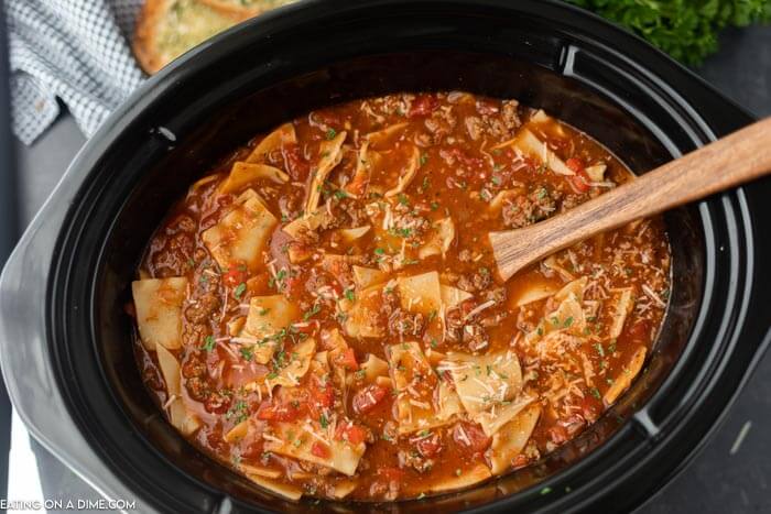 a crock pot full of this lasagna soup with a wooden spoon in it 