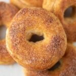 A close-up of air fryer donuts covered with cinnamon sugar, stacked on top of each other. The donuts have a golden-brown color and visible sugar crystals on the surface.