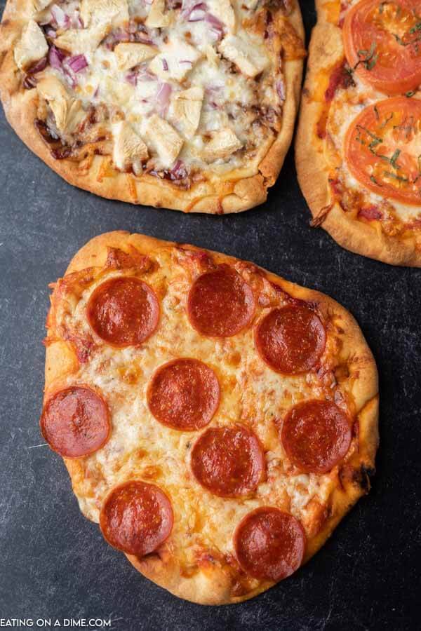 Close up image of 3 flatbread pizza including, pepperoni. 