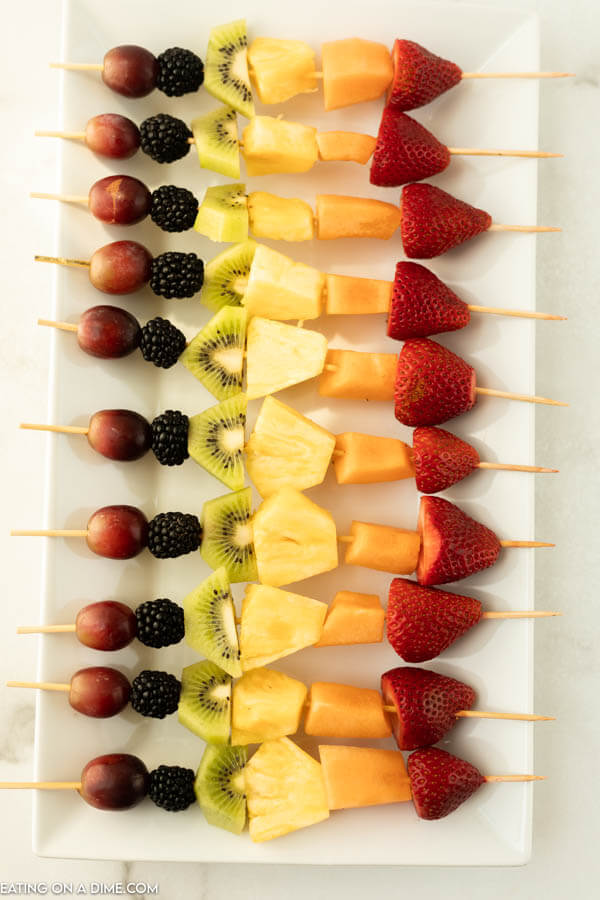 Fruit Skewers prepared and lined up on a white serving platter 