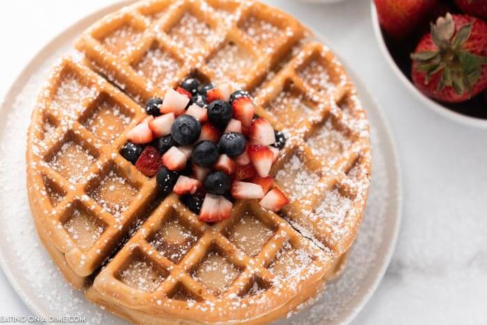Gluten Free waffles topped with powdered sugar and diced up fresh fruit 