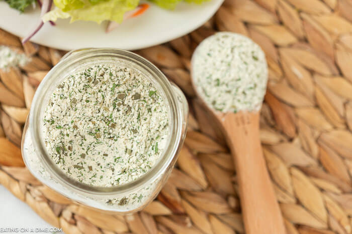 A tablespoon of the ranch dressing mix next to a jar full of the homemade ranch seasoning mix. 