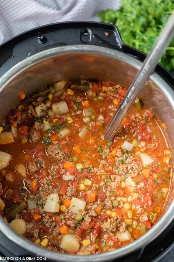 The instant pot full of this vegetable beef soup topped with fresh parsley 