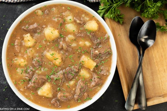 Beef and Potato Stew in a white bowl with two spoons on the side