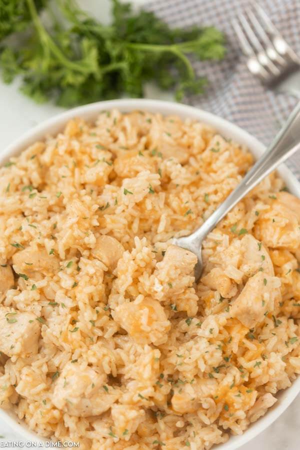 A large bowl of chicken and rice with a fork in the middle of it.  