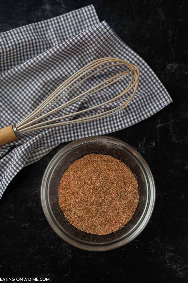 A small bowl of homemade steak seasoning with a whisk next to it 