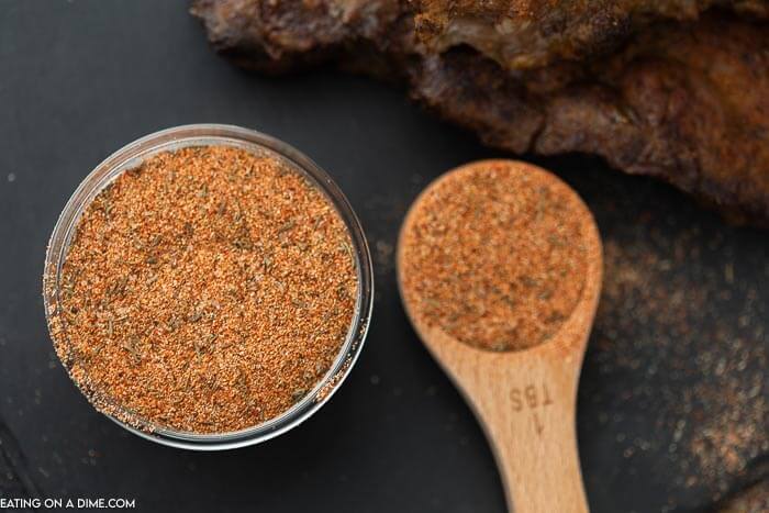 A small bowl of steak seasoning with a wooden tablespoon next to it filled with the seasoning mixture as well. 
