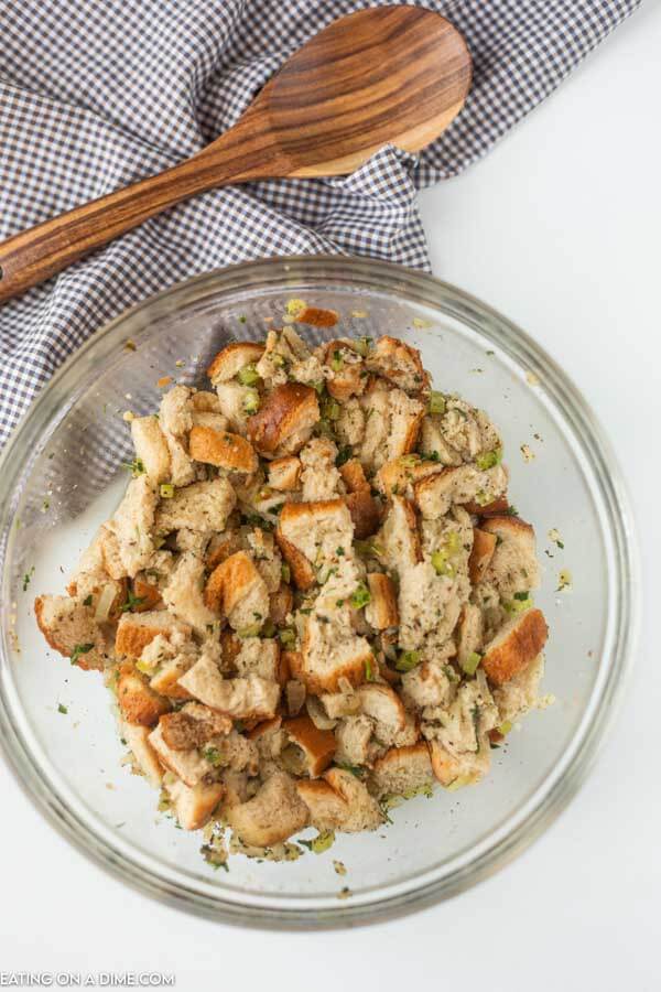 combining the bread mixture with the veggie mixture in a bowl with a wooden spoon