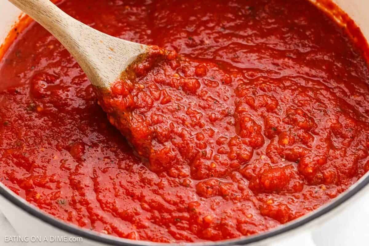 Marinara sauce in a large pot with a wooden spoon.