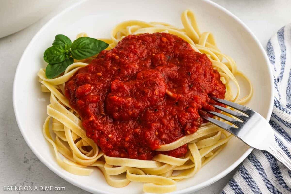 Red sauce topped fettuccine on a plate.