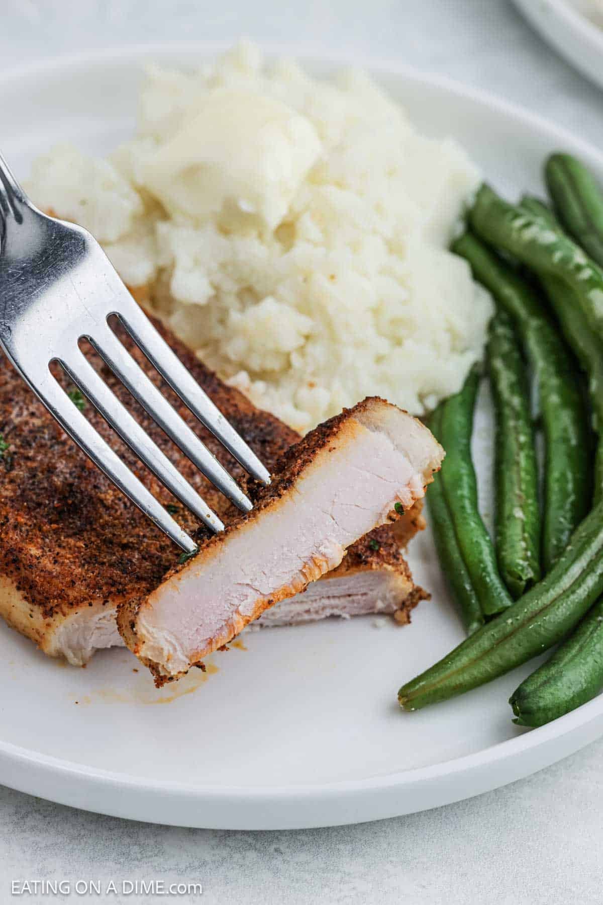 Pork chops, mashed potatoes and green beans on a white plate. 