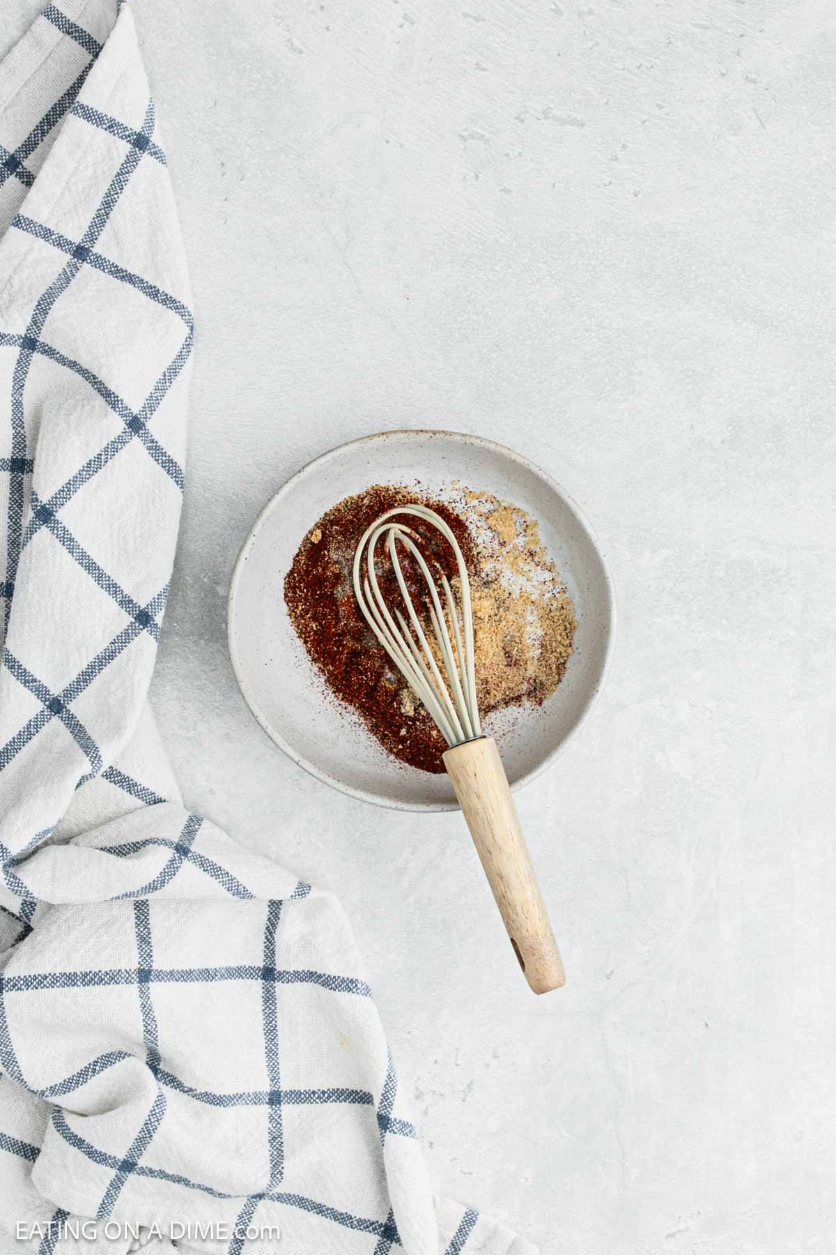 Combining the spices together in a bowl with a whisk. 