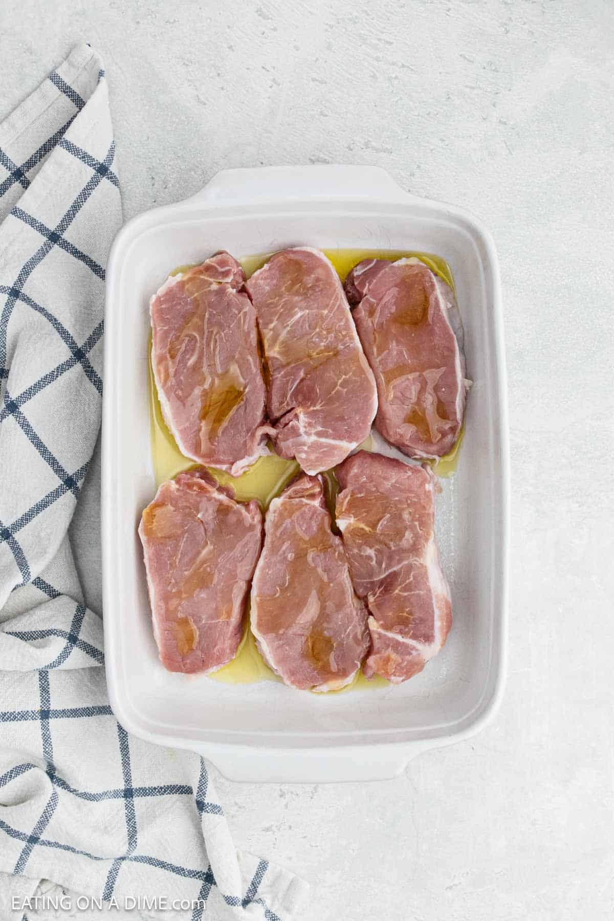 Pork chops in a baking dish drizzled with oil. 