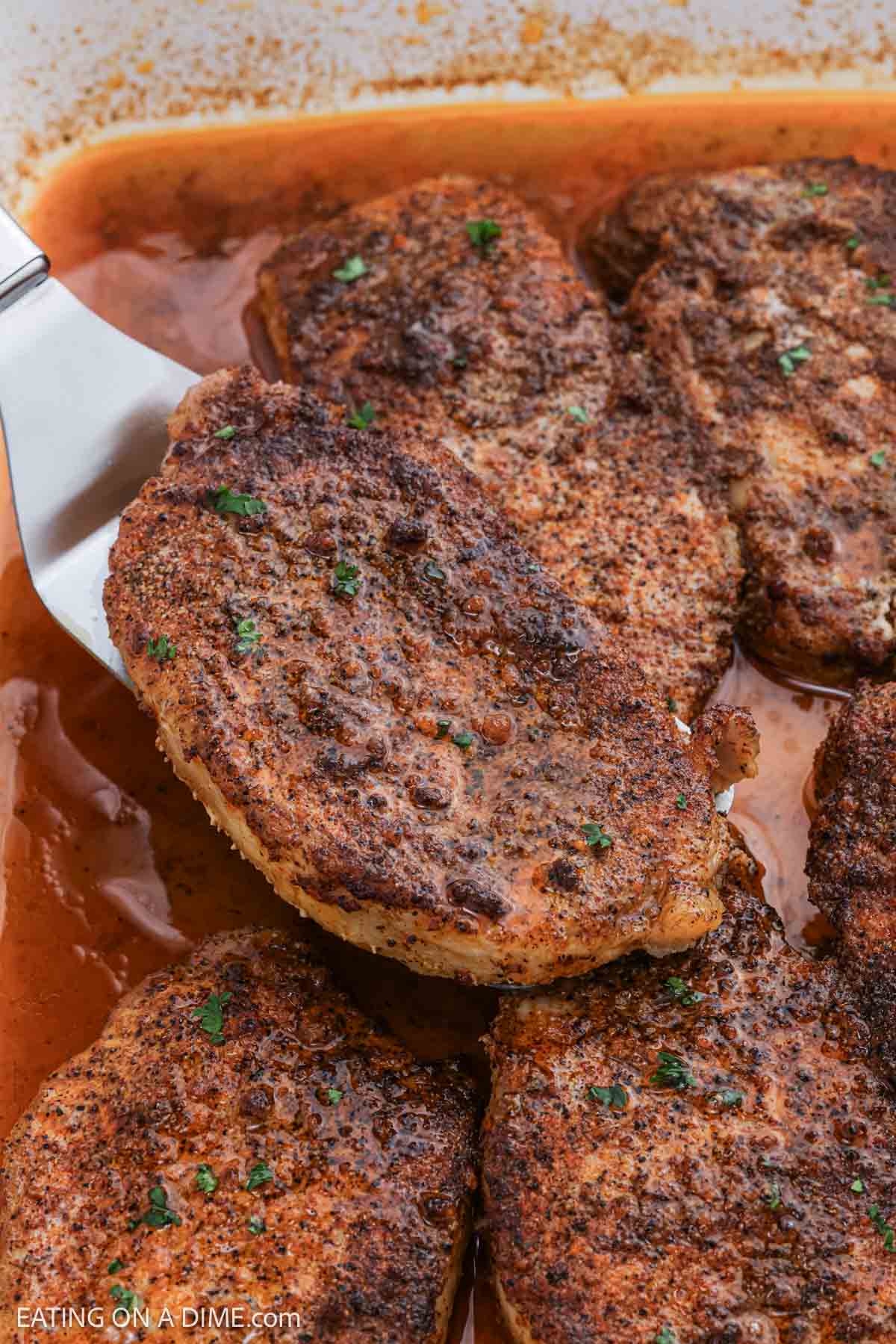 Close up image of golden brown pork chops in a baking dish. 
