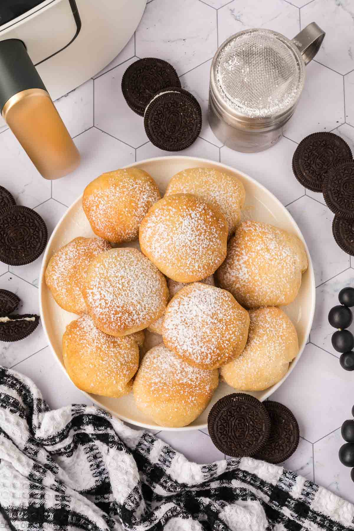 Air Fried Oreos sprinkled with Powdered Sugar stacked on a plate