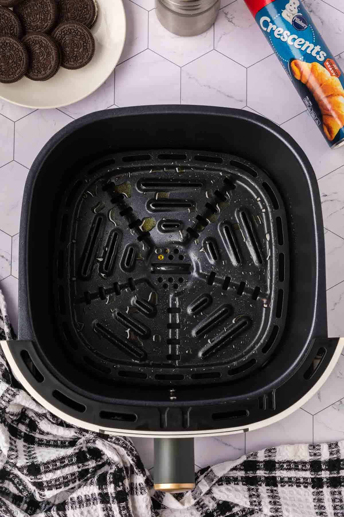 Air Fryer Basket with oil, place of Oreos on the side with a can of Crescent Rolls