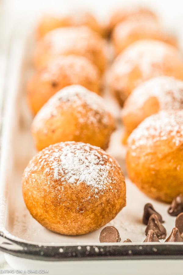 Close up image of deep fried cookie dough on a white plate with chocolate chips. 