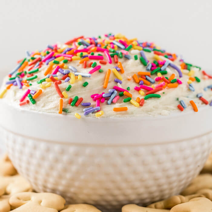 Close up image of funfetti dip in a white bowl with sprinkles and animal crackers on the side. 