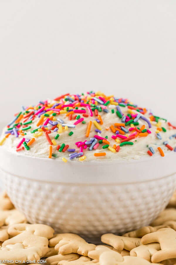 Close up image of funfetti dip in a white bowl with sprinkles and animal crackers on the side.