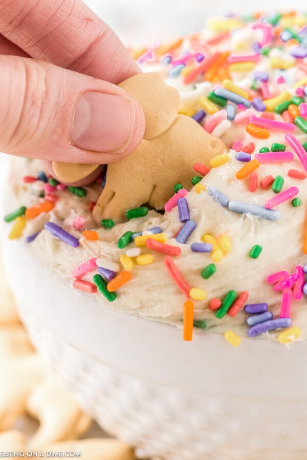 Close up image of funfetti dip in a white bowl with sprinkles and animal crackers on top. 