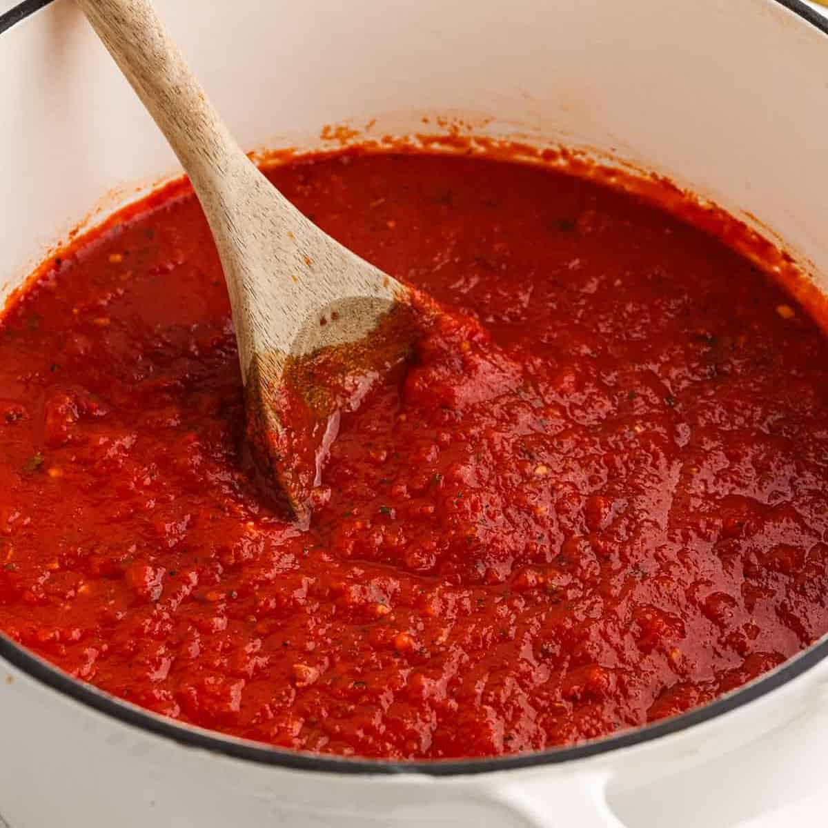 Marinara sauce in a large pot with a wooden spoon.