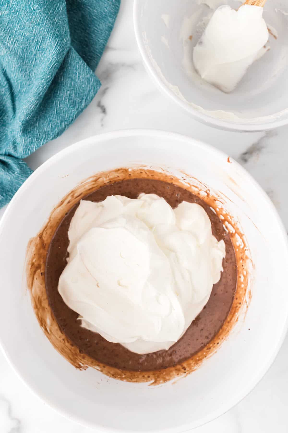 Whipped cream added to bowl of chocolate mixture.