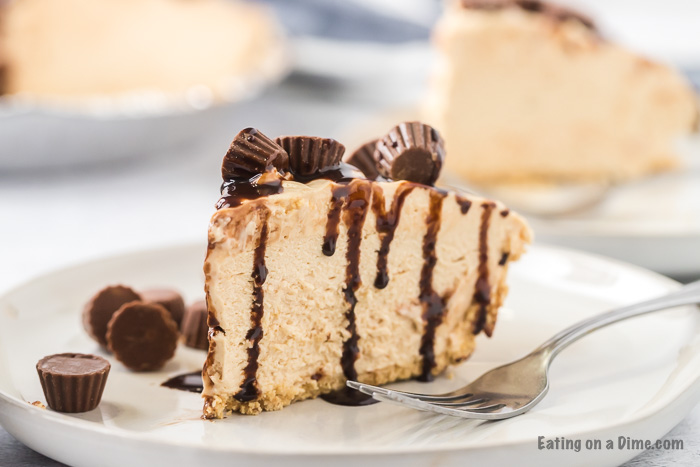 Close up image of a slice of peanut butter pie topped with mini peanut butter cups on a plate with a fork. 