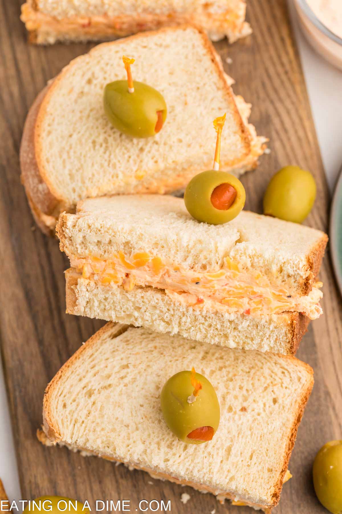 Pimento Cheese cut in half on a cutting board topped with green olives