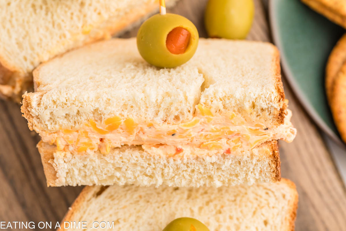 Pimento Cheese Sandwich cut in half topped with a green olive