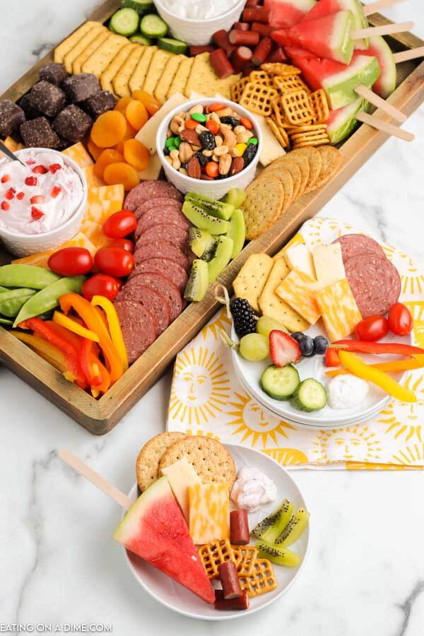 Summer charcuterie board with fruit, vegetables, chocolate, nuts and mote.