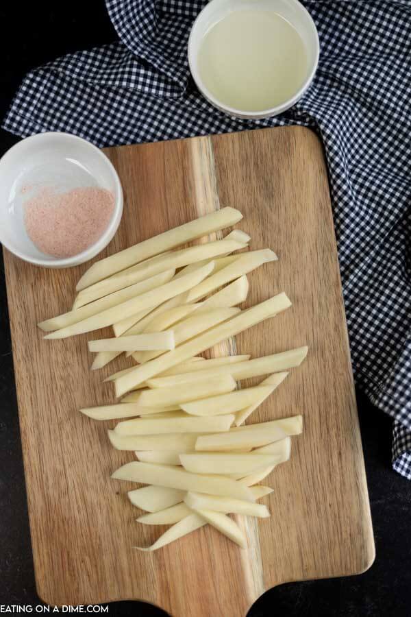 Potatoes cut into strips on cutting board. 