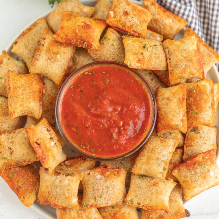 Pizza rolls on a platter with pizza sauce. 