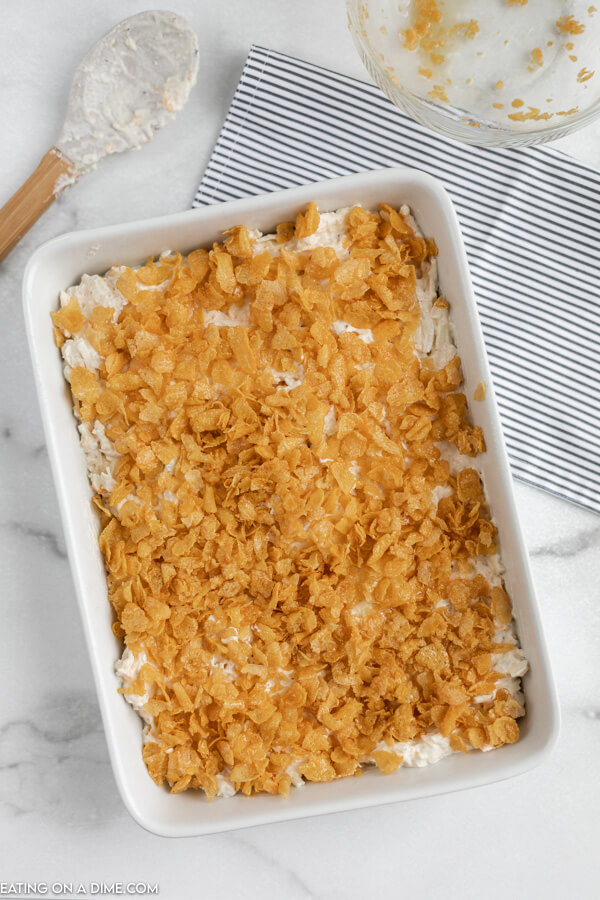 Close up image of cheesy chicken hashbrown casserole in a 9x13 white dish. 