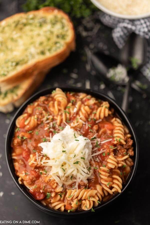 Close up image of Lasagna Soup in a black bowl with a side of bread. 