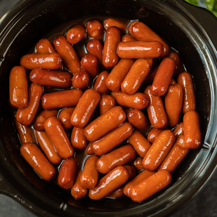 Close up of BBQ Little Smokies in a small black crock pot. 
