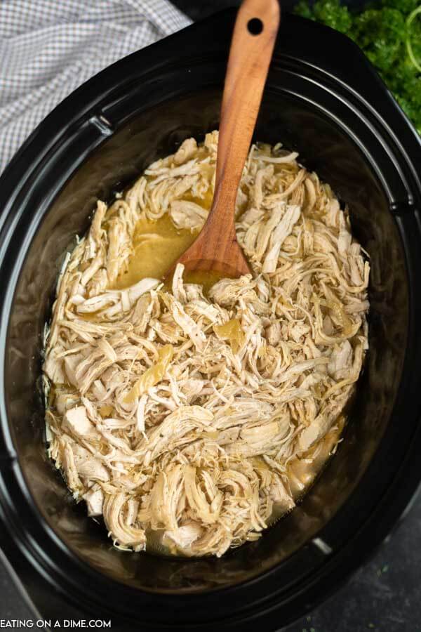 Close up image of Mississippi Chicken in a crock pot with a brown spoon. 