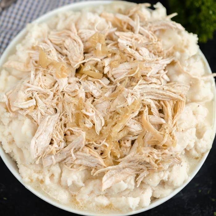 Close up image of Mississippi Chicken in a bowl on top of mash potatoes. 