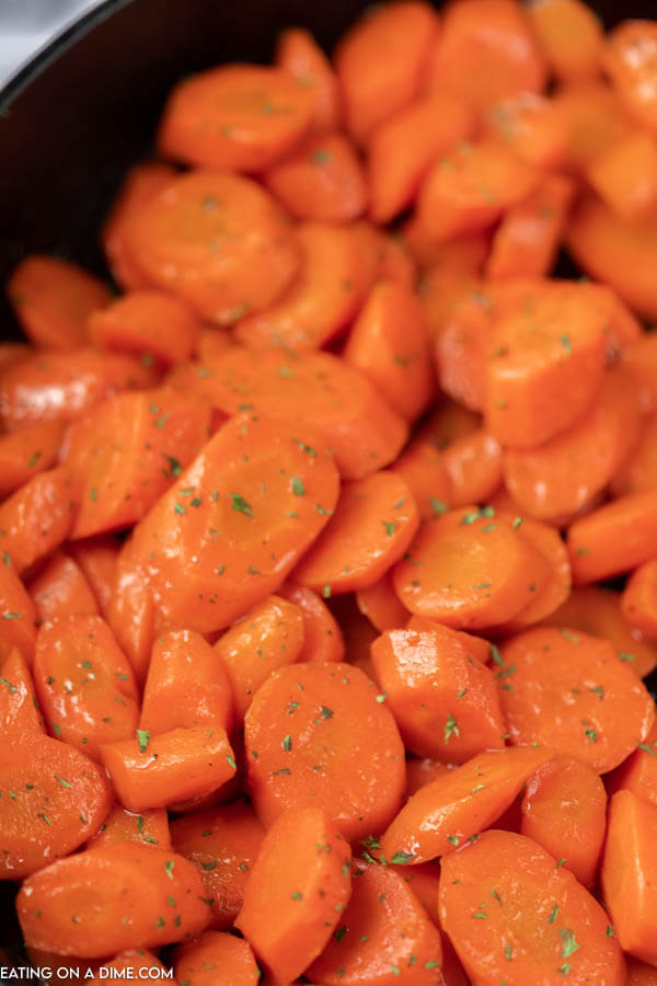 Close up image of brown sugar glazed carrots in a skillet. 