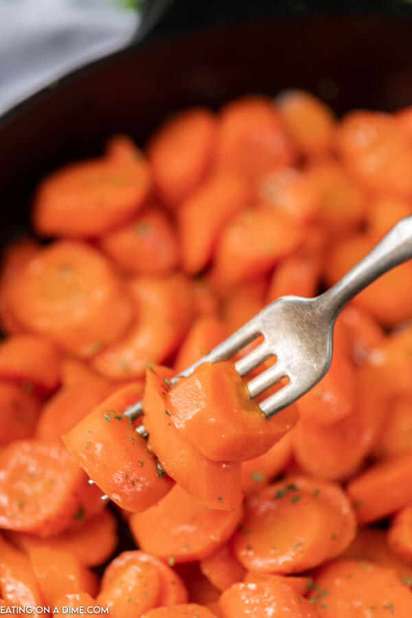 Close up image brown sugar glazed carrots with a serving on the fork. 