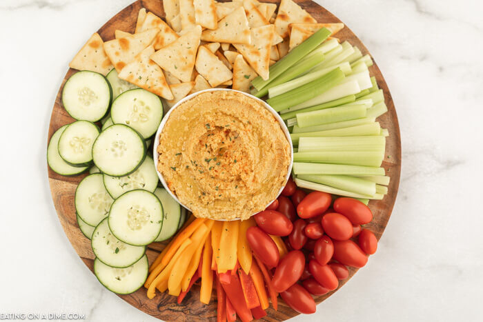 Platter of veggies and pita chips with a bowl of hummus.