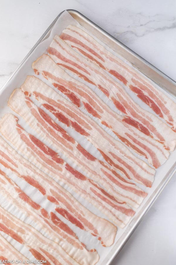 uncooked bacon on baking sheet