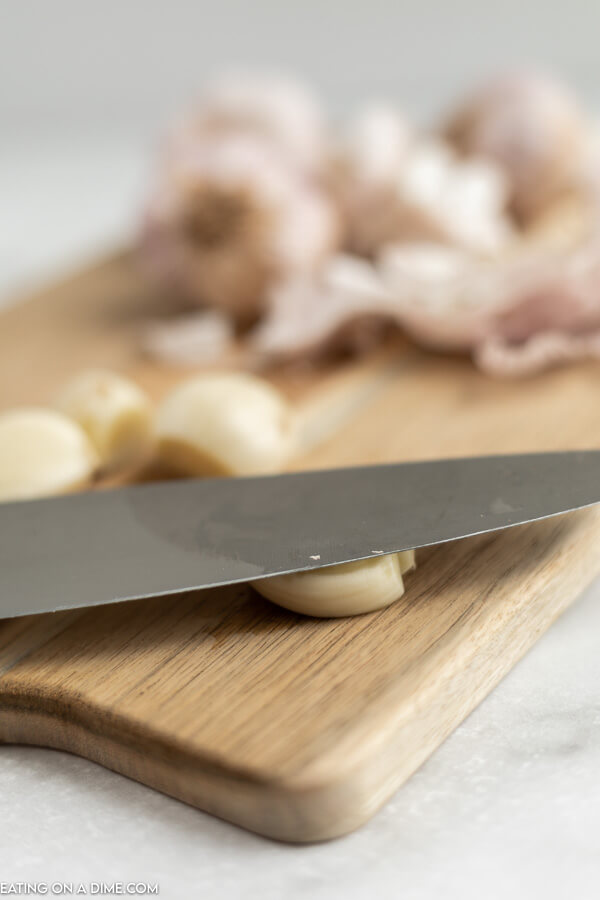 Close up image a knife in the process of mince garlic. 