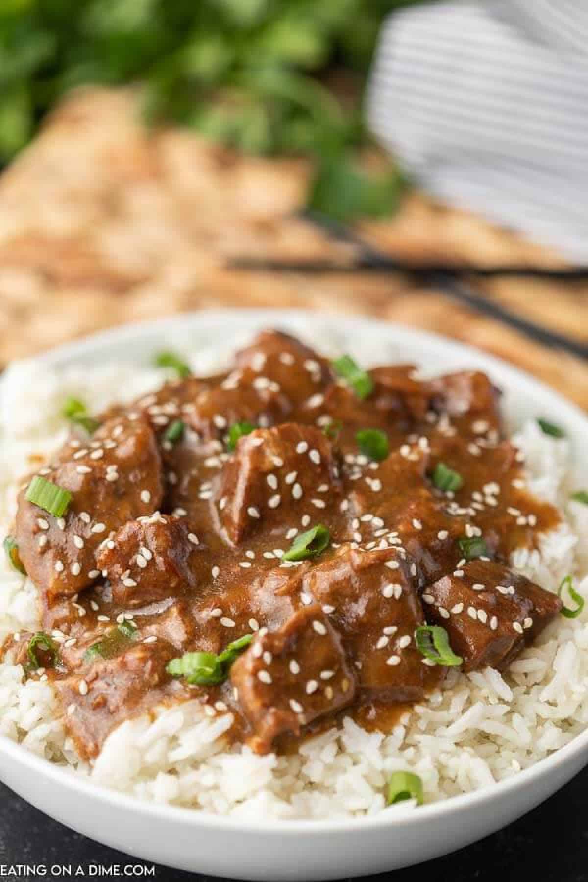 Teriyaki Beef over rice with chop sticks in the back ground 