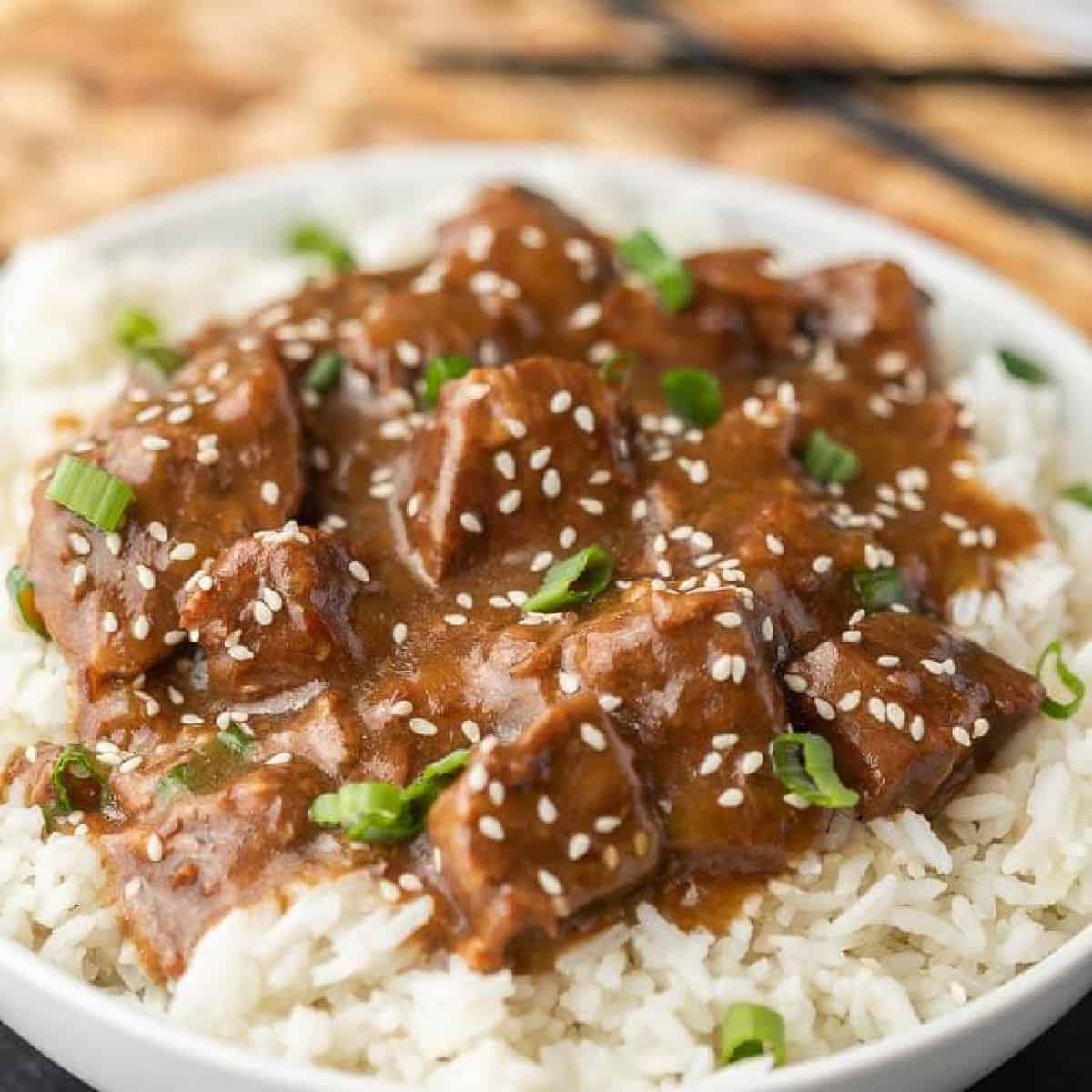Teriyaki Beef over rice topped with sesame seeds and green onions 