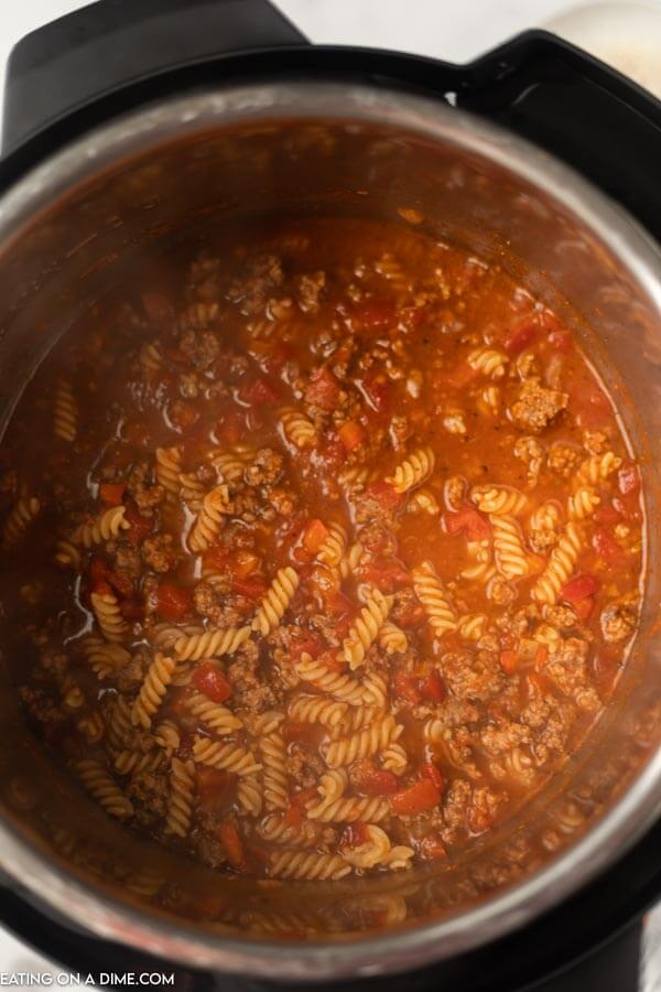 Close up image of noodles, sauce, tomatoes and sauce in the instant pot. 