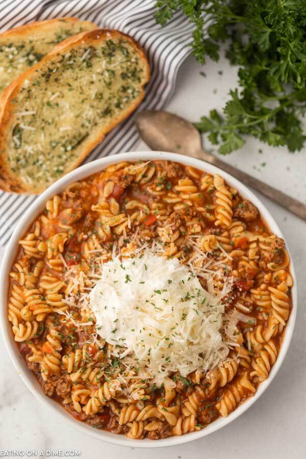 Close up image of a bowl of lasagna soup with a slice of french bread and spoon. 
