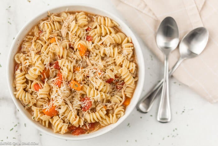 Close up image of a bowl of Italian Chicken Soup with two silver spoons. 